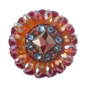 Peut inclure: Une broche en forme de fleur avec des pierres rouges, orange et bleues, avec un grand cabochon carré rouge au centre.