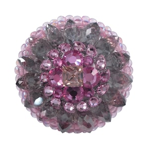 Peut inclure: Une broche en perles rose et grise avec un grand cristal rose au centre.