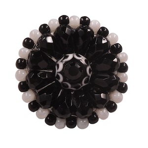 May include: A black and white beaded flower brooch with a central black crystal surrounded by white beads.