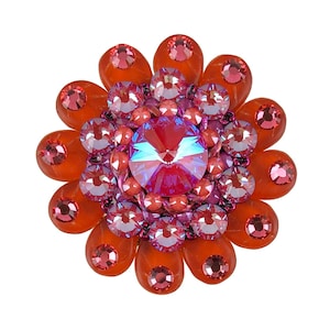 Könnte beinhalten: Eine blütenförmige Brosche mit einem zentralen, regenbogenfarbenen, violetten Kristall, umgeben von kleineren rosa und orangefarbenen Kristallen.