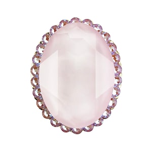 以下が含まれることがあります： ファセットカットされたデザインの大きな楕円形のピンクの宝石。宝石は、虹色の小さな紫色のラインストーンの装飾的な縁で囲まれています。