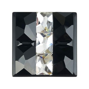 May include: A black square-shaped decorative knob with three clear crystal rhinestones in the centre.