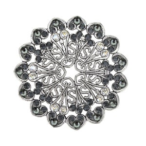 May include: A silver-toned brooch with a circular design. The brooch is decorated with black and clear rhinestones set in a filigree pattern.