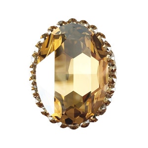 以下が含まれることがあります： クリアなファセットの縁取りが施された、大きなオーバル型のゴールド調のラインストーンです。
