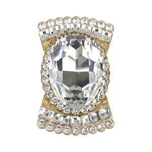 以下が含まれることがあります： クリアなファセットカットの大きな宝石が、小さなクリアな宝石で囲まれた、ゴールドトーンのリングです。