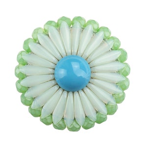 Puede incluir: Un broche de flor con cuentas blancas y verdes y un centro azul.