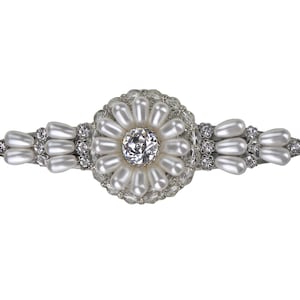 May include: A silver hair clip with a large pearl and rhinestone flower design.