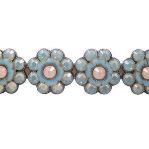May include: A row of four blue and white flower-shaped hair clips with crystal accents.