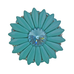 May include: A turquoise blue flower brooch with a sparkling blue crystal in the center.
