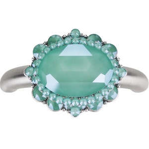 May include: A silver ring with a large oval-shaped green gemstone surrounded by smaller green gemstones.