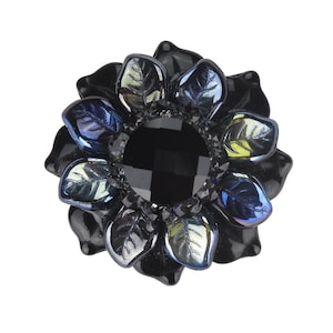 May include: Black flower-shaped hair clip with a large, black, faceted gemstone in the center. The petals of the flower are iridescent and have a blue, green, and purple hue.