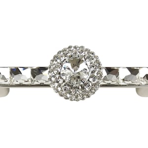 Könnte beinhalten: Ein silberner Schubladenzug mit einem Kristall in der Mitte, umgeben von kleineren Kristallen. Der Zug ist rechteckig mit einer glatten Oberfläche.