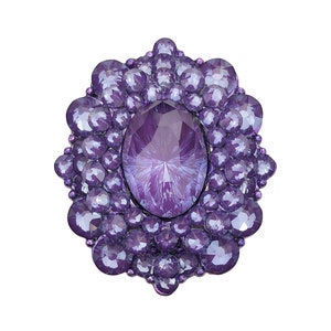 May include: A purple jeweled brooch with a large oval-shaped center stone surrounded by smaller round stones.