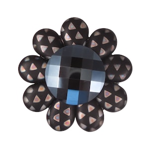 以下が含まれることがあります： 中央に青いファセットカットの幾何学的な宝石がついた、黒い花の形をしたブローチ。花びらは小さな三角形の繰り返し模様になっています。