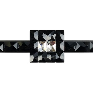 Könnte beinhalten: Ein schwarzer Türgriff mit einem quadratischen Kristall-Akzent in der Mitte. Der Griff ist aus Metall und hat eine strukturierte Oberfläche.