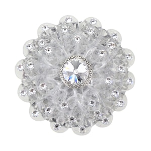 以下が含まれることがあります： 中央に大きな透明なクリスタルをあしらった、銀と透明なクリスタル製のフラワーブローチです。