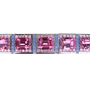 May include: A silver hair clip with five pink and blue gemstones. The gemstones are set in a square shape and are surrounded by smaller pink gemstones.