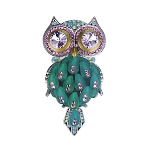 Puede incluir: Un broche de búho verde y plateado con diamantes de imitación rosas y transparentes. Los ojos del búho están hechos de diamantes de imitación transparentes con un engaste dorado.