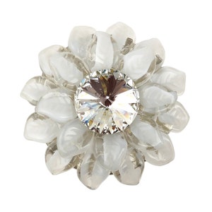 Peut inclure: Une broche en forme de fleur blanche avec un cristal transparent au centre.