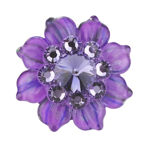 以下が含まれることがあります： 中央に大きなクリスタル、周囲に小さなクリスタルをあしらった紫色の花の形をしたブローチ。 花びらは半透明の紫色で、濃い紫色の葉脈が入っています。 ジュエリーアクセサリーです。