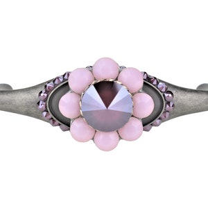 Puede incluir: Una pulsera de plata con un diseño de flor rosa. La flor tiene un gran cristal morado oscuro en el centro y está rodeada de cristales rosas más pequeños.
