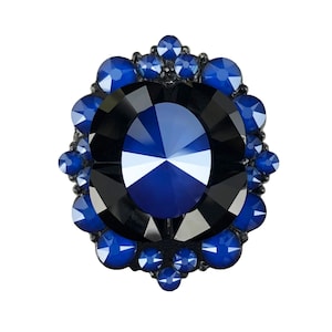 Könnte beinhalten: Ein großer, dunkelblauer, facettierter Edelstein, umgeben von einem Heiligenschein aus kleineren, blauen Edelsteinen.