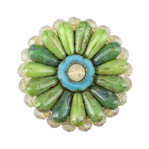 May include: A green and blue flower-shaped brooch with a clear rhinestone center.