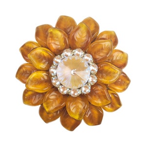 May include: A gold-toned brooch shaped like a sunflower with a clear crystal centre.