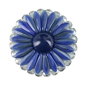 Könnte beinhalten: Eine blaue Glasblumenbrosche mit einem dunkelblauen Zentrum und klaren Glasperlen an den Rändern.