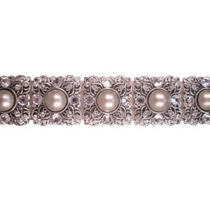 Peut inclure: Un bracelet argenté avec cinq breloques carrées, chacune ornée d'une fausse perle entourée de strass transparents.