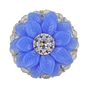 以下が含まれることがあります： クリスタルの中心に囲まれたクリアラインストーンで飾られた青い花のブローチ