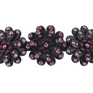 May include: Black hair clip with three flower-shaped designs. Each flower is adorned with purple and red rhinestones.