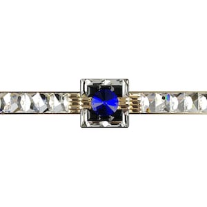 Könnte beinhalten: Ein goldfarbener Schubladenzug mit einem quadratischen Kristallzentrum, das mit einem blauen Edelstein verziert ist. Der Zug ist mit klaren Kristall-Akzenten verziert.