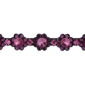 May include: A black hair clip with a row of five pink flower-shaped embellishments, each with a central pink rhinestone surrounded by smaller pink rhinestones.