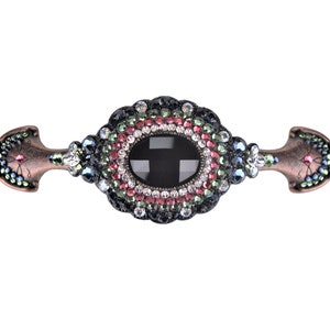 Op de afbeelding: Een decoratieve kastknop met een zwarte ovale edelsteen omringd door een ring van kleurrijke strass. De knop is gemaakt van metaal met een koperen afwerking en heeft aan elk uiteinde een puntig ontwerp.