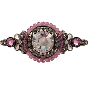 Op de afbeelding: Een roze en zilveren haarspeld met een groot, helder kristal in het midden.