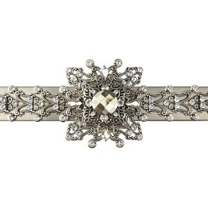 Può includere: Un fermacortina argentato con un grande centro decorato e incrostato di cristalli. Il fermacortina ha un design floreale delicato.