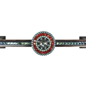 Może przedstawiać: Dekoracyjny uchwyt do szafki z okrągłym wzorem ozdobionym czerwonymi, niebieskimi i przezroczystymi kryształkami. Uchwyt jest wykonany z metalu i ma szczotkowane brązowe wykończenie.