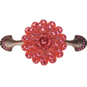 Puede incluir: Un tirador de cajón decorativo rojo y dorado con un diseño de flor. La flor está hecha de plástico transparente con diamantes de imitación rojos.