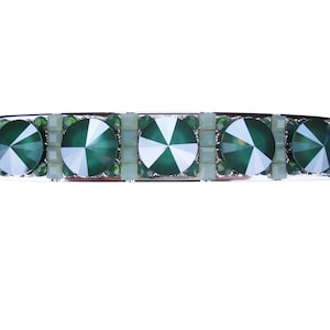 Op de afbeelding: Een zilveren haarspeld met vier groene facetgeslepen strassstenen in een rij.