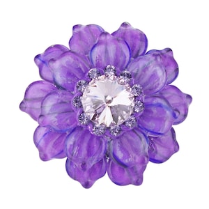 May include: A purple flower-shaped brooch with a large clear rhinestone in the center surrounded by smaller rhinestones.