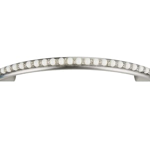 Puede incluir: Un tirador de armario plateado con una fila de cuentas blancas nacaradas en la parte superior.