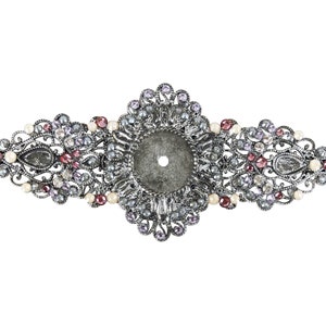 May include: A silver filigree brooch with a round center and a variety of clear, purple, and pink rhinestones.