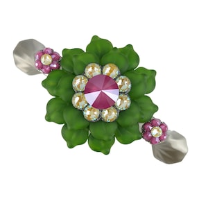 Może przedstawiać: Zielony pierścionek w kształcie kwiatu z dużym czerwonym kamieniem szlachetnym otoczonym mniejszymi, przezroczystymi kamieniami szlachetnymi. Pierścionek ma dwa mniejsze, różowe akcenty kwiatowe po obu stronach.