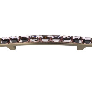 May include: A curved, gold-toned cabinet pull with a row of pink crystal-like stones.