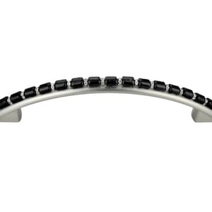 Może przedstawiać: Srebrny, wygięty uchwyt do szafki z czarnym, prostokątnym wykończeniem z kryształu.