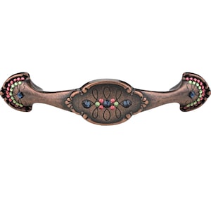 Może przedstawiać: Klamka do szafki wykonana z miedzi z ozdobnym wzorem z niebieskimi, zielonymi i czerwonymi kamieniami szlachetnymi.