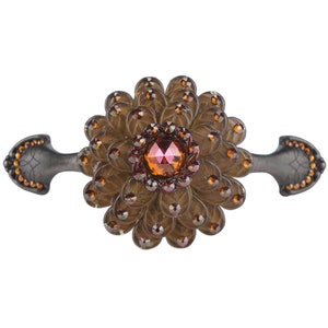 Puede incluir: Un pomo de armario de metal marrón y negro con un gran diseño de flor marrón adornado con una joya roja en el centro.