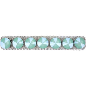 May include: A silver barrette with a row of light green rhinestones.