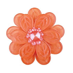 Könnte beinhalten: Eine korallenfarbene Blumenbrosche mit einem rosafarbenen Strassstein in der Mitte. Die Blume ist aus Kunststoff und hat ein mehrschichtiges Design.